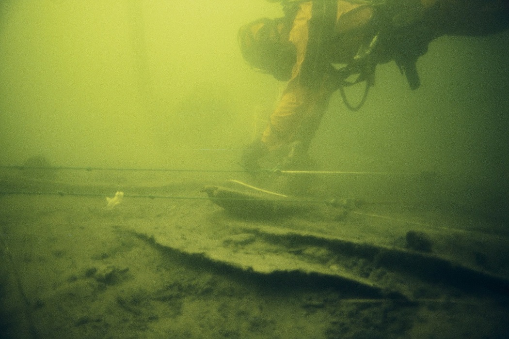 Kuva: Sukeltaja mittaamassa kaaria. Näkyvissä paarpuurin laudoitusta sekä kaari 4 ja 5. Pentti Eskolin 1992