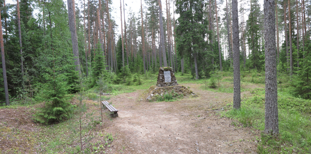 Kuva: Hautausmaan keskelle on pystytety muistomerkki, jonka ympärillä on maastakasattuja harjanteita ja väliojia joihin nälkään kuolleet haudattiin vuonna 1868. Teemu Mökkönen 17.6.2019