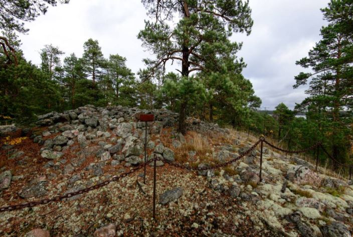 Kuva: Röykkiön ympärillä on kettinki ja vieressä kuparinen muinaisjäännöstaulu. Vesa Laulumaa 2015